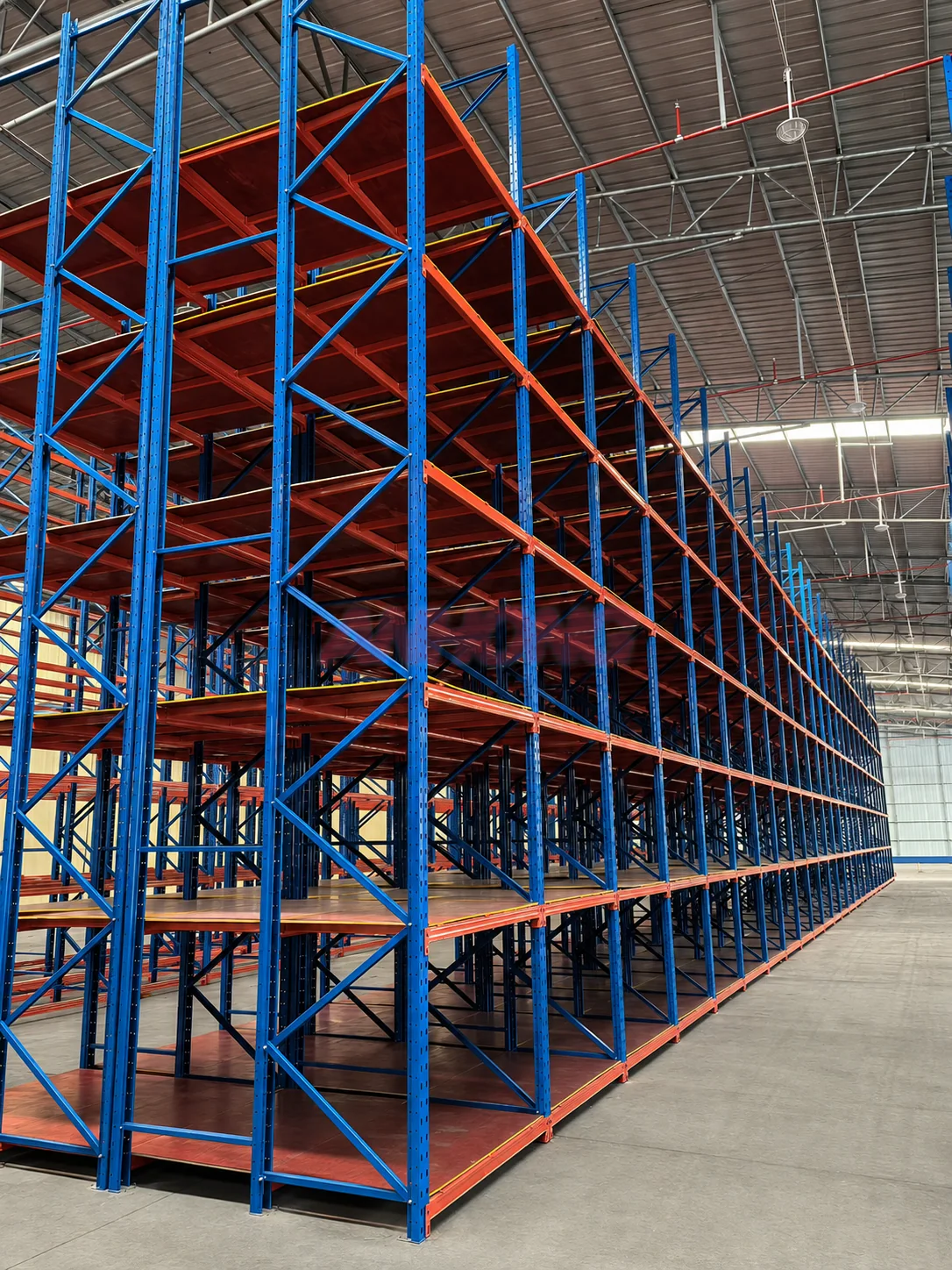 Multi-level warehouse racking installation with blue frames and orange shelves